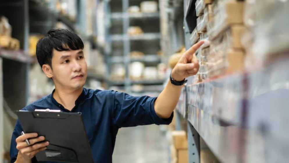 sourcing-nos-services Groupe de 3 personnes regardant une tablette dans un environnement de travail, avec des colis emballés